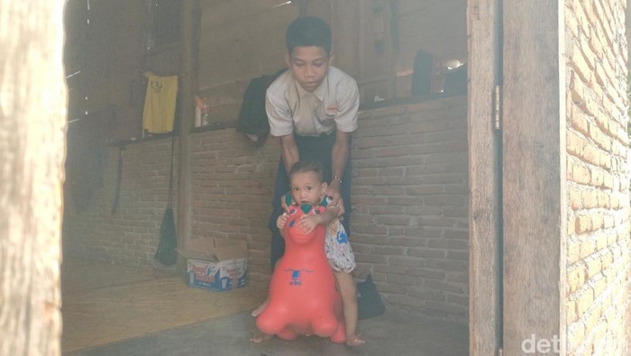 1763982379974-siswa-smp-di-polman-muhammad-supri-15-menggendong-adiknya-yang-sempat-dibawa-ke-sekolah-1763975858011_169